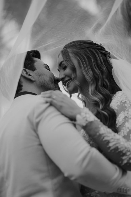 Free Intimate black and white portrait of a couple embracing under a veil. Stock Photo