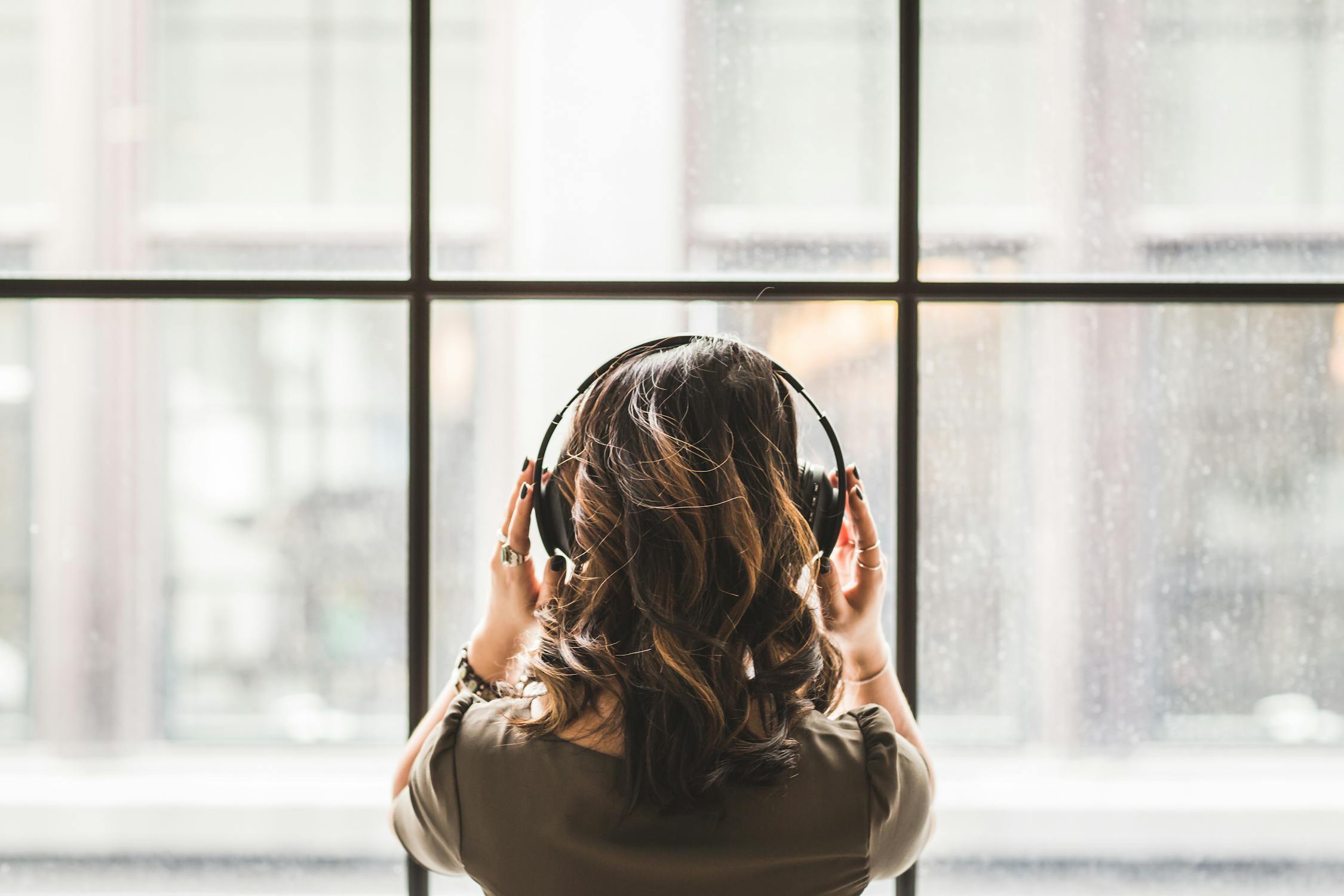Woman facing window with headphones on