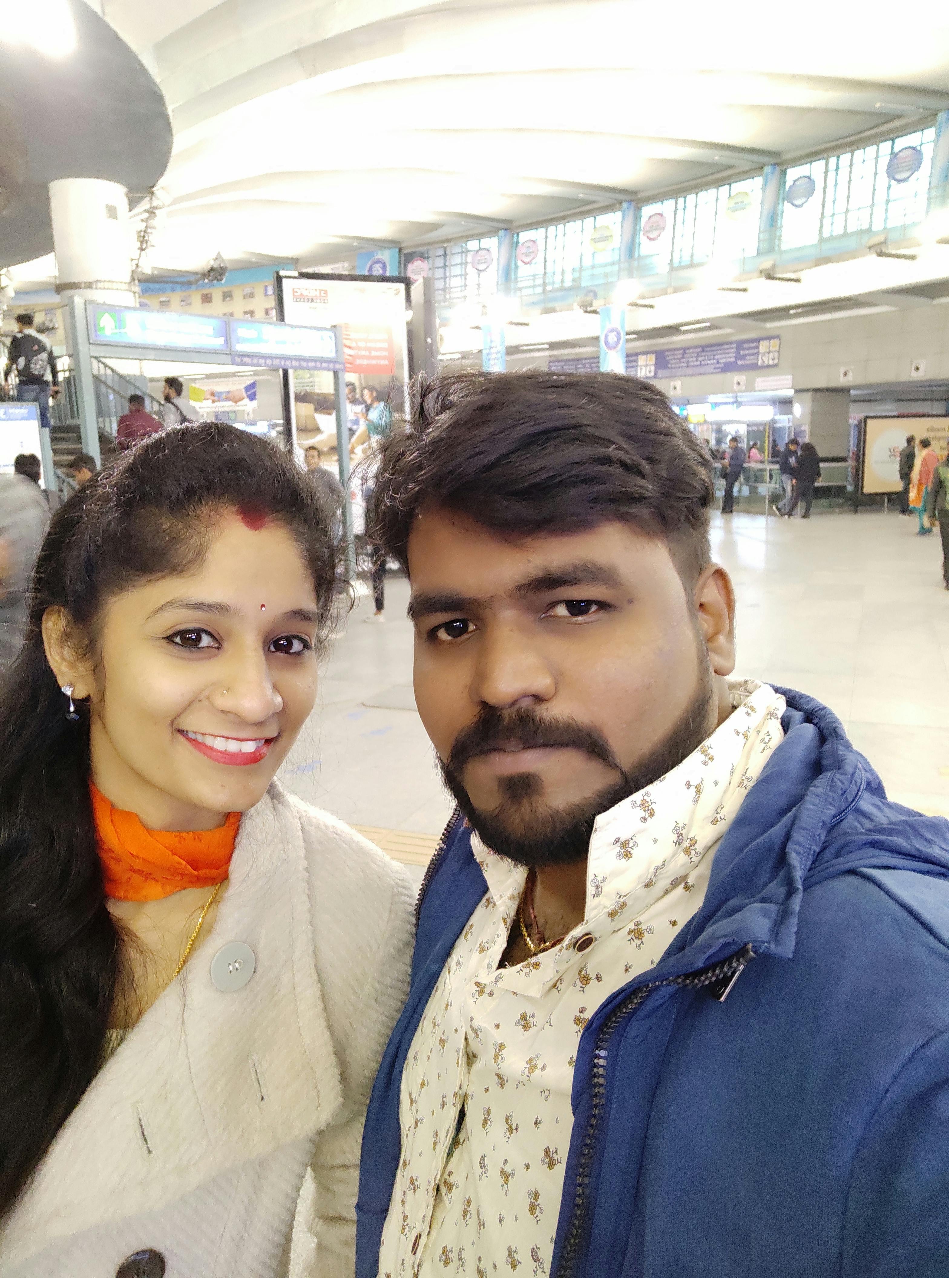 Person with headphones looking at a cityscape through a window during sunset, laptop nearby