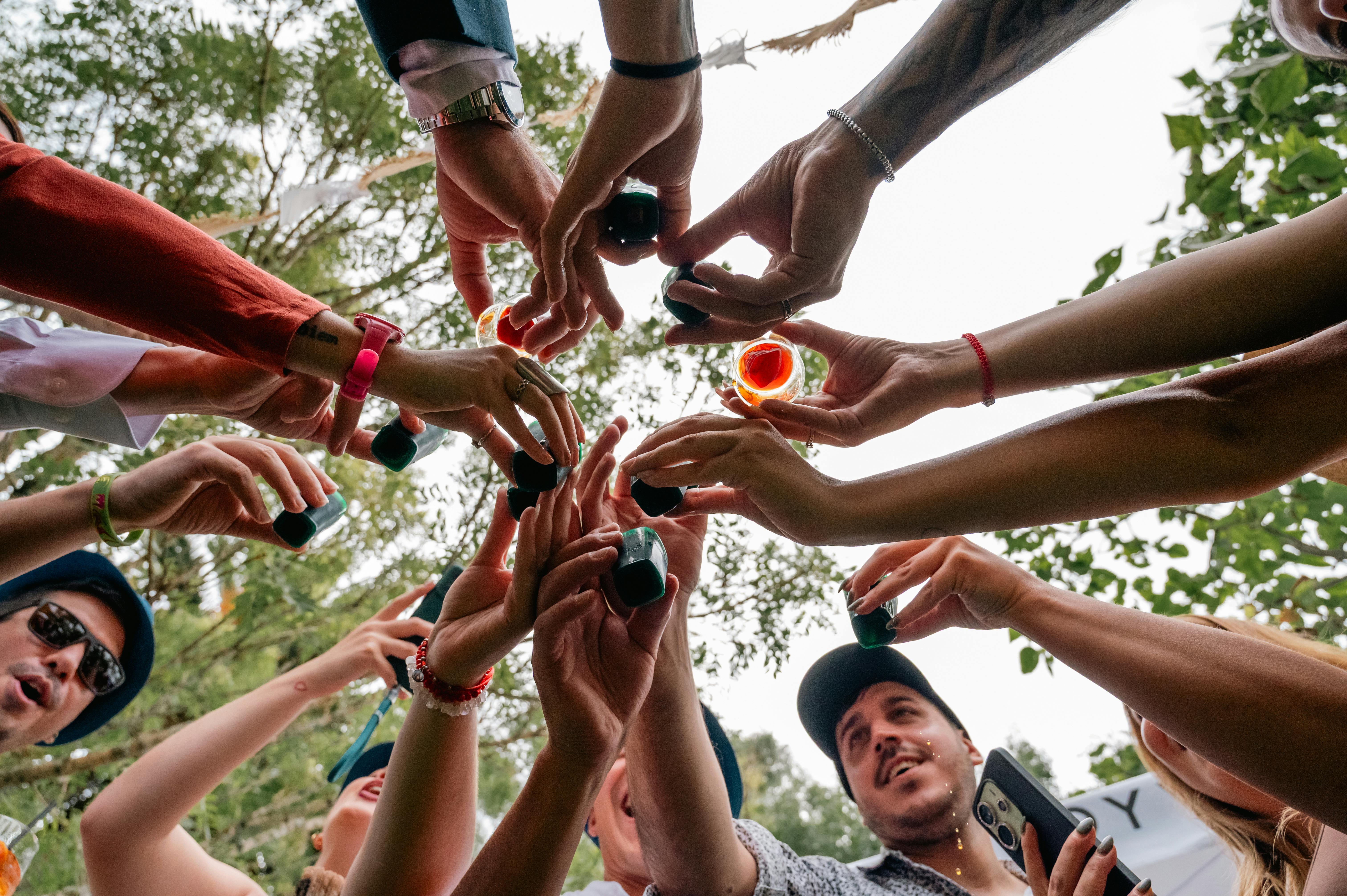 A lively group of friends raising colorful shots outdoors, capturing a festive toast.