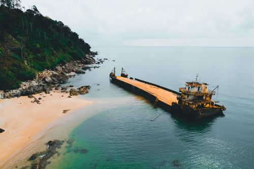Free Aerial view of an abandoned shipwreck on a tranquil tropical beach with lush greenery and azure water. Stock Photo