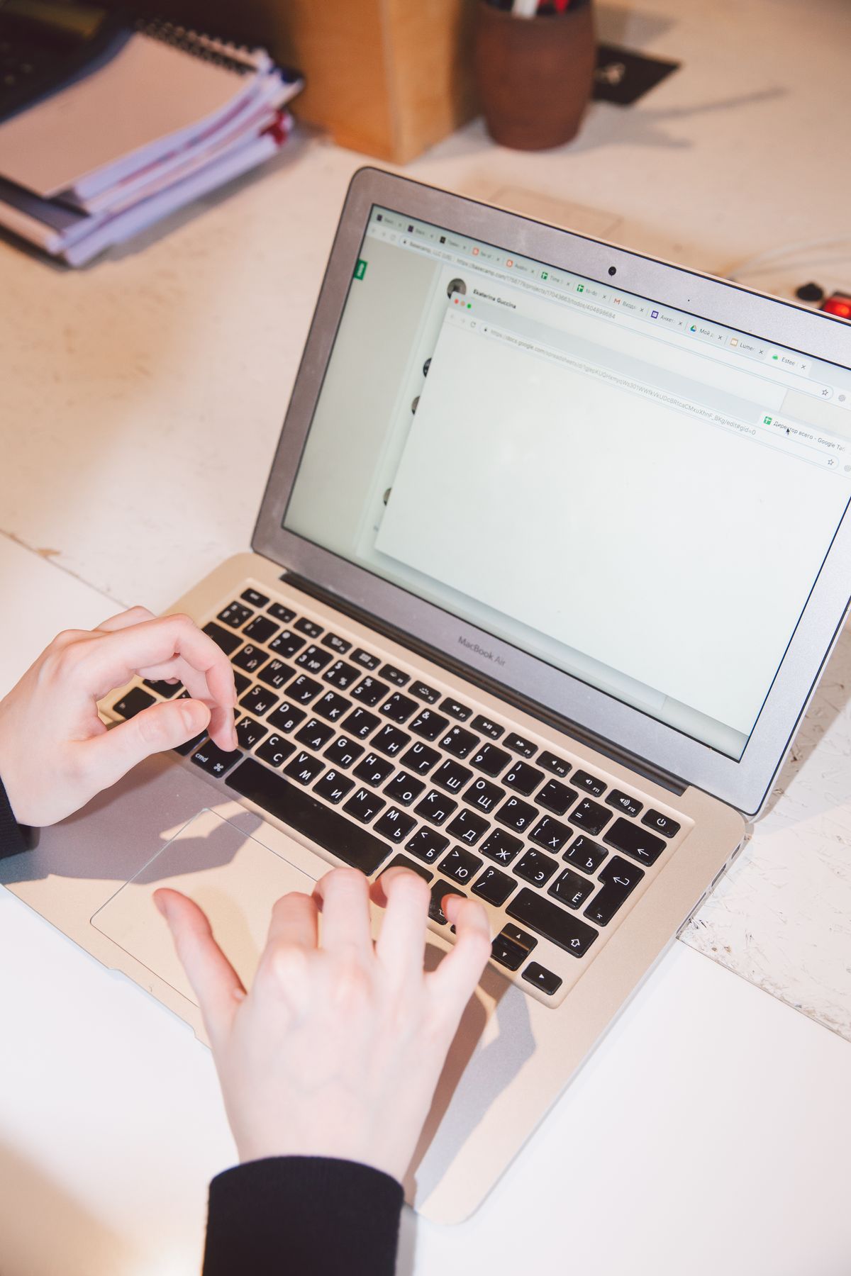 Mâini care tastează pe un laptop, la un birou de lucru