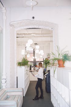 A contemporary office interior featuring a woman working amidst plants and modern decor.