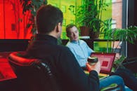 两名男子在现代室内环境中，拿着笔记本电脑和咖啡进行临时工作会议