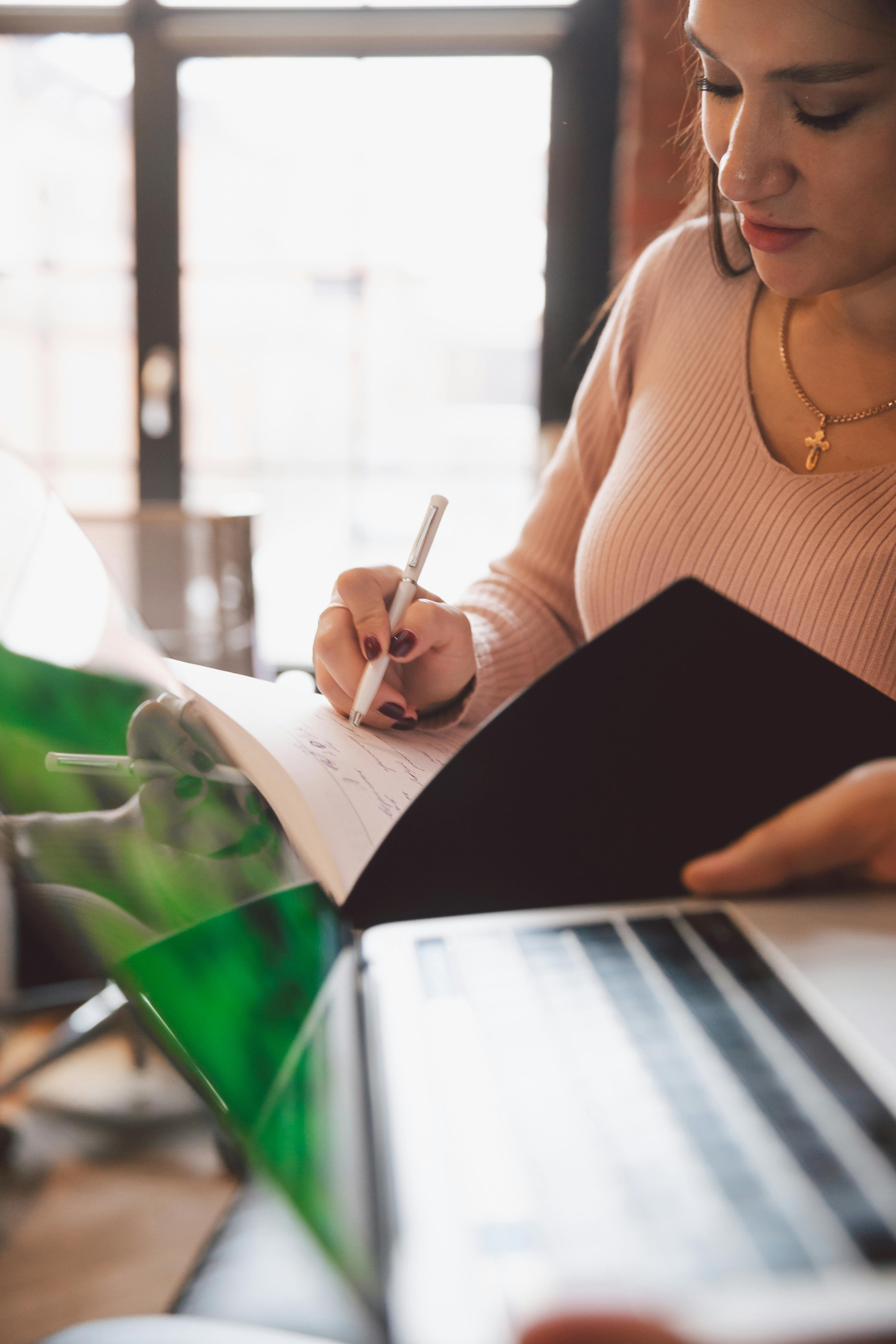 photo of woman writing on notebook