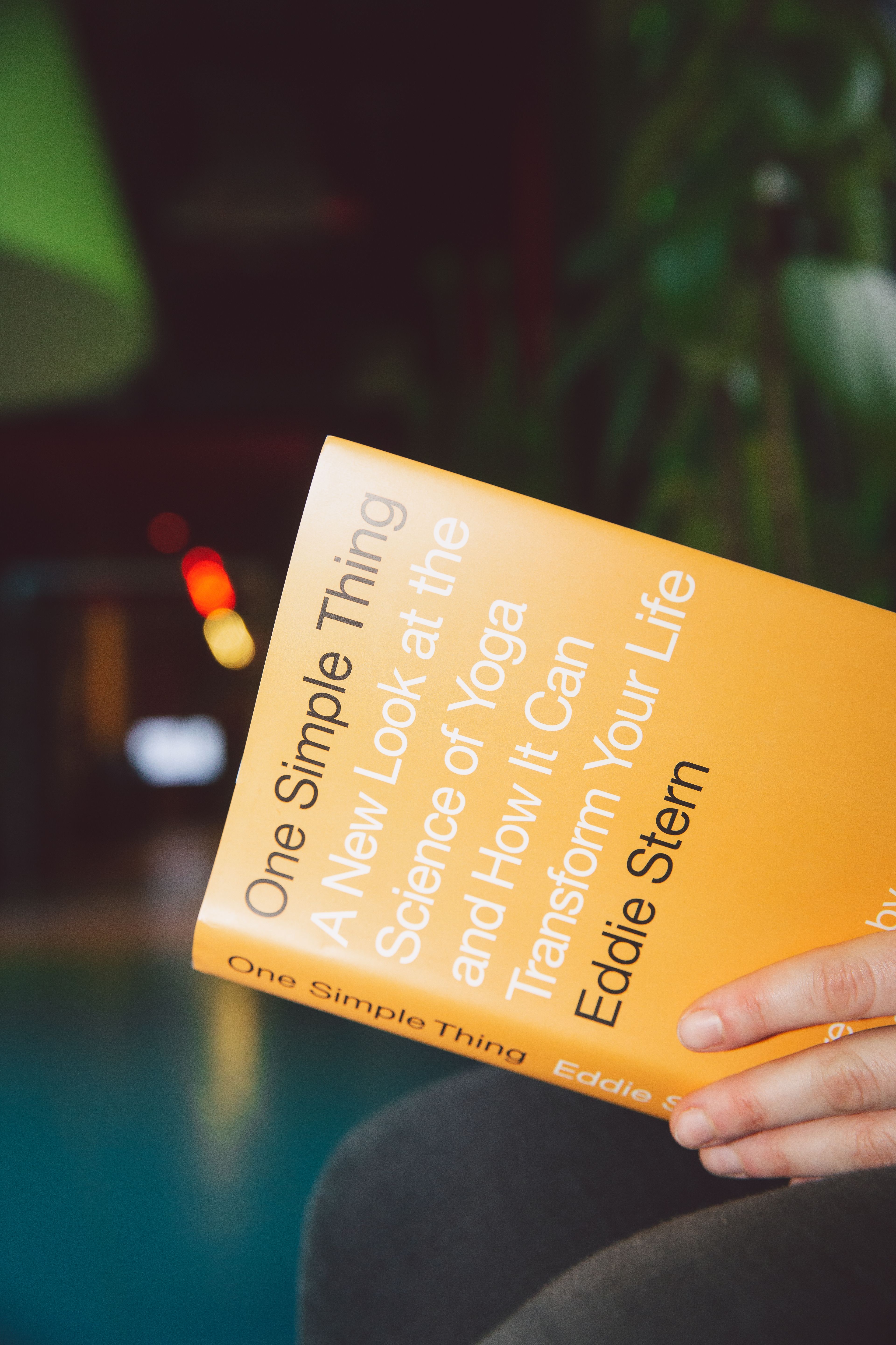 Close-up of a hand holding a yoga book, offering insights into science and personal transformation.