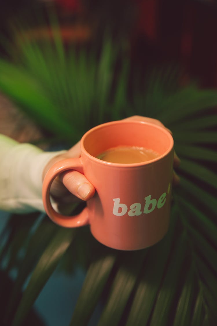 Person Holding Pink Ceramic Mug