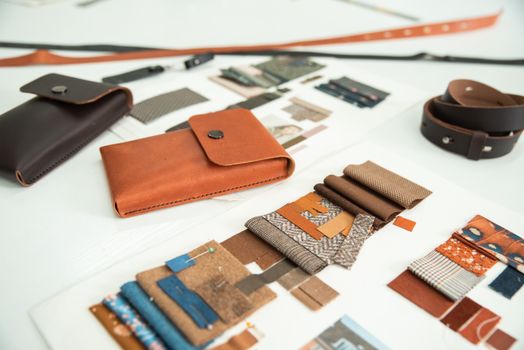 Artistic layout of leather goods and fabric samples in a design workspace.