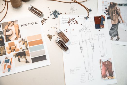 Creative fashion workspace featuring design sketches, mood boards, and beads on a desk.