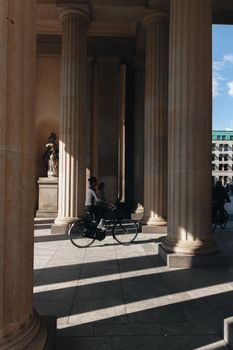 A cyclist passes between the towering columns of the iconic Brandenburg Gate in Berlin.
