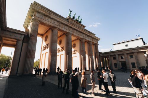 Free Tourists gather at the historic Brandenburg Gate in Berlin, Germany under bright sunshine. Stock Photo