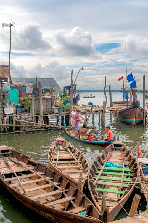 Free Colorful traditional boats and a family in a harbor in Indonesia, showcasing local life and culture. Stock Photo