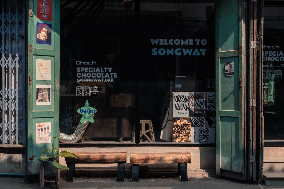 Entrance to Songwat Specialty Chocolate in Bangkok, showcasing local art and welcoming signage.