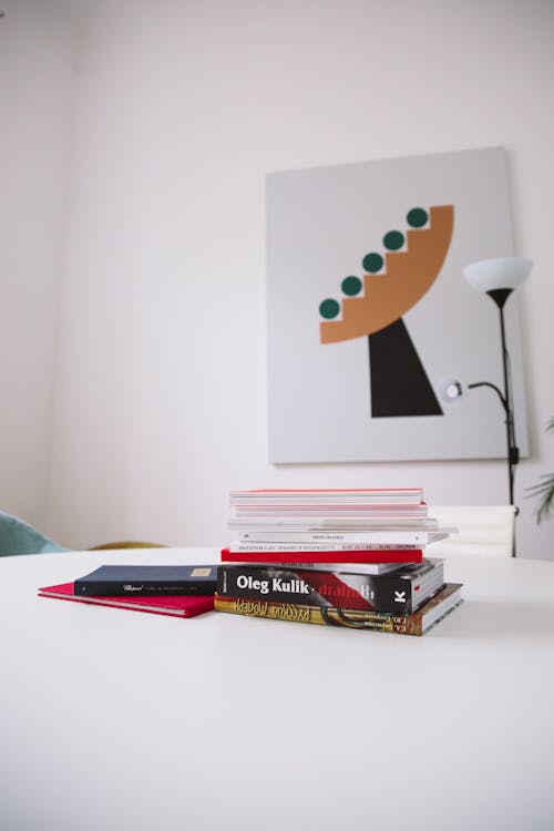 Фотография стопки книг на белом столе