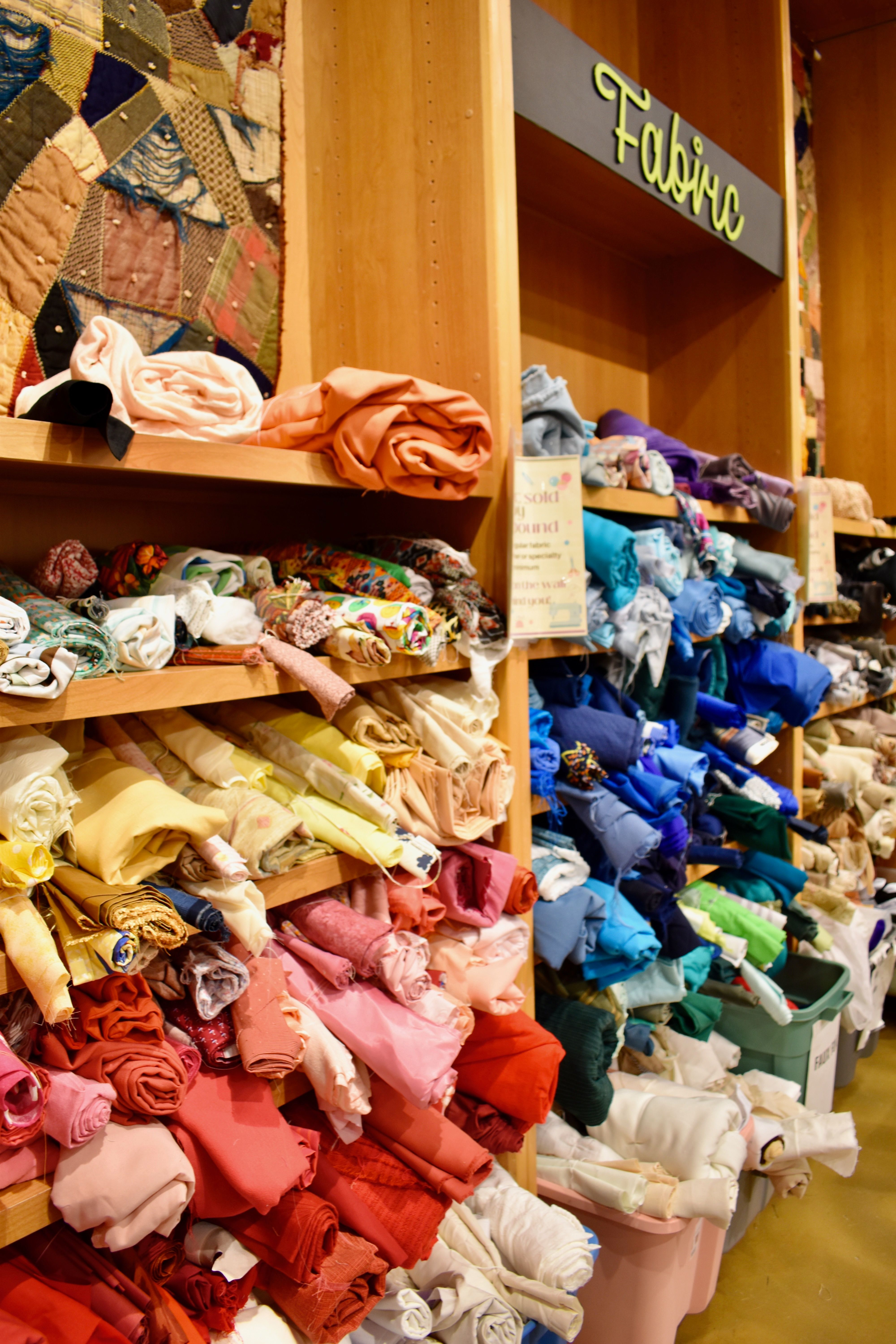 Vibrant array of fabrics neatly organized in a craft store, showcasing creativity.