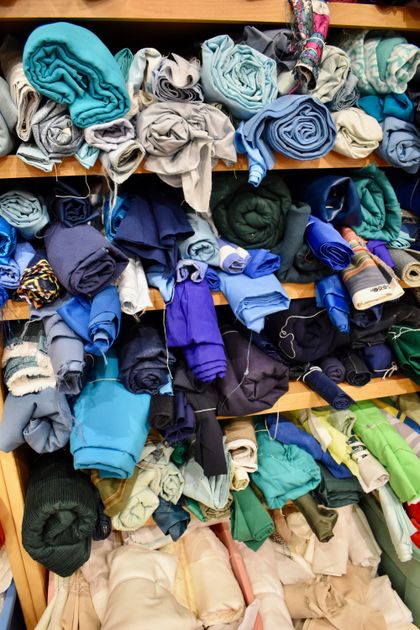 Vải xếp chồng nhiều lớp trên kệ trong cửa hàng vải
