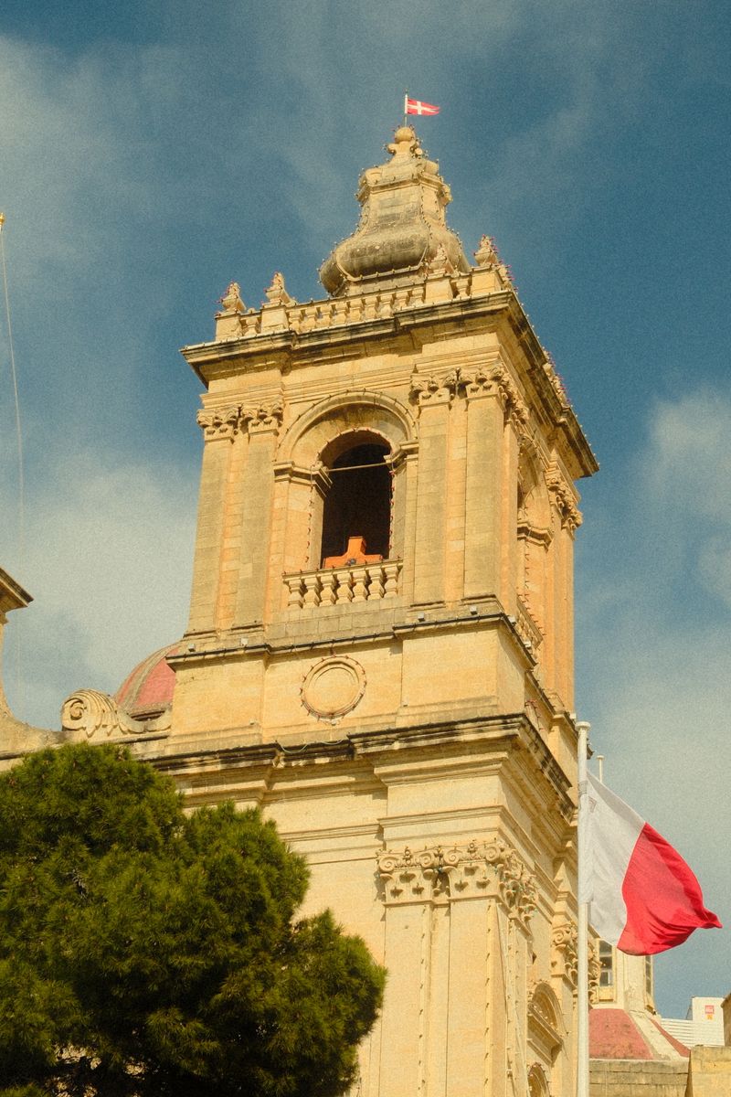 Maltese church steeple flying the flag of Malta during festa season
