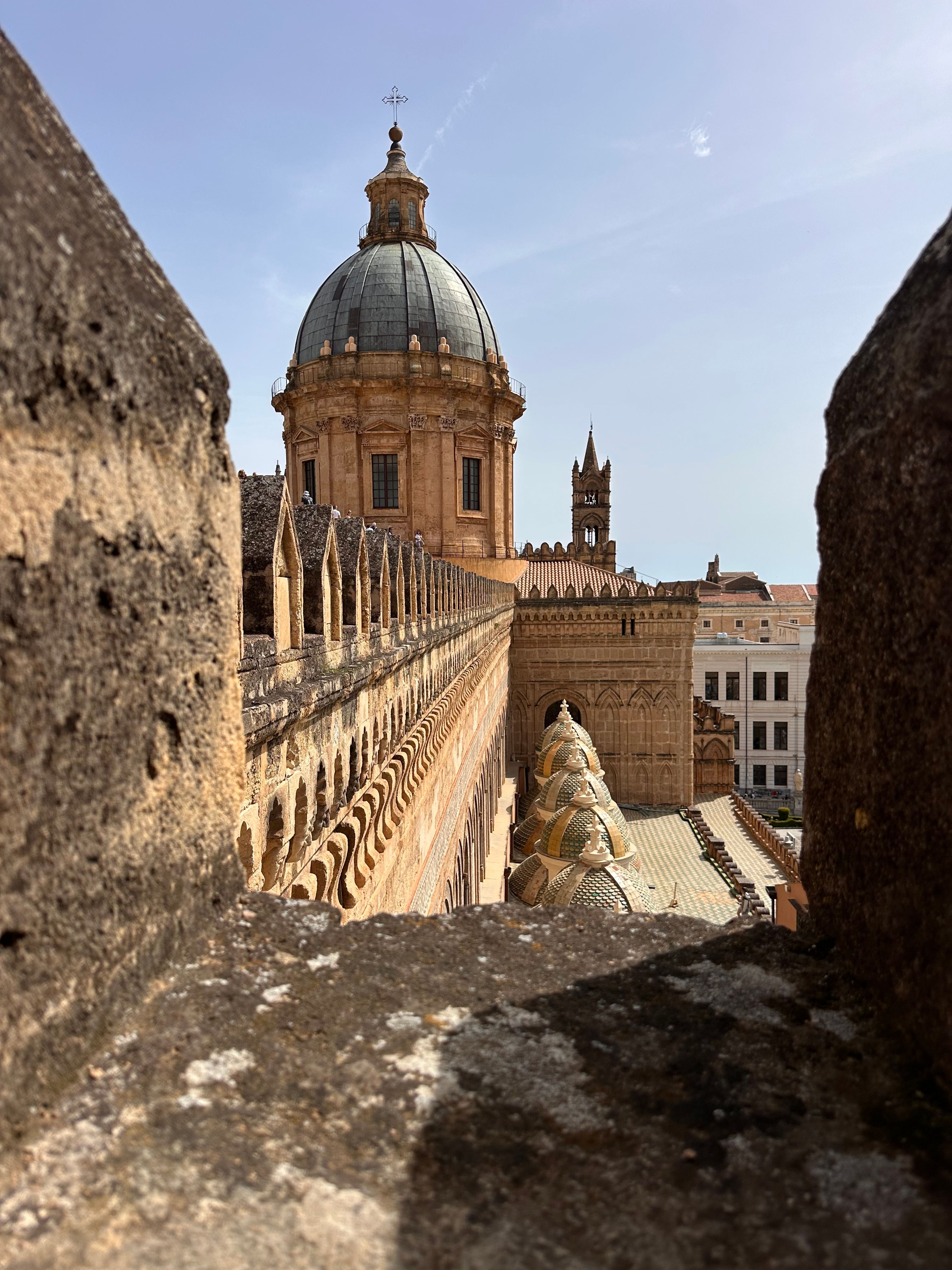View of Palermo Cathedral's dome and tower through ancient stone walls.