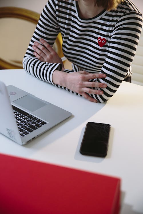 Person in Black and White Striped Long Sleeve Shirt Using Macbook Pro