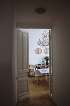 A stylish study room with elegant decor viewed through an open door.