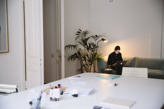 A person working on a laptop in a cozy, modern home office with ambient lighting.