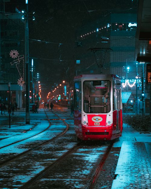 Free A bright red tram on a snowy street at night with holiday decorations and lights. Stock Photo