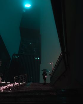 A solitary person with an umbrella in a moody urban night scene, surrounded by towering skyscrapers.