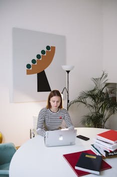 A woman works remotely at a table with a laptop in a stylish home office.