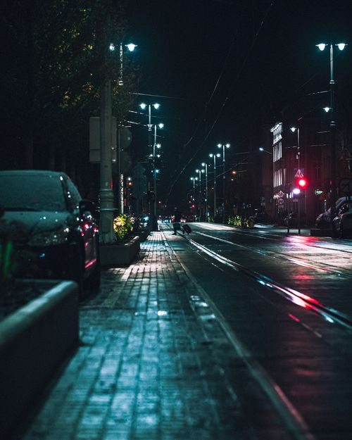 Free Moody nighttime city street with illuminated streetlights and wet pavement. Stock Photo