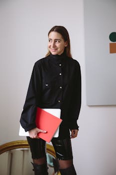 在现代环境中，一位穿着黑色服装的时尚女性正拿着笔记本电脑