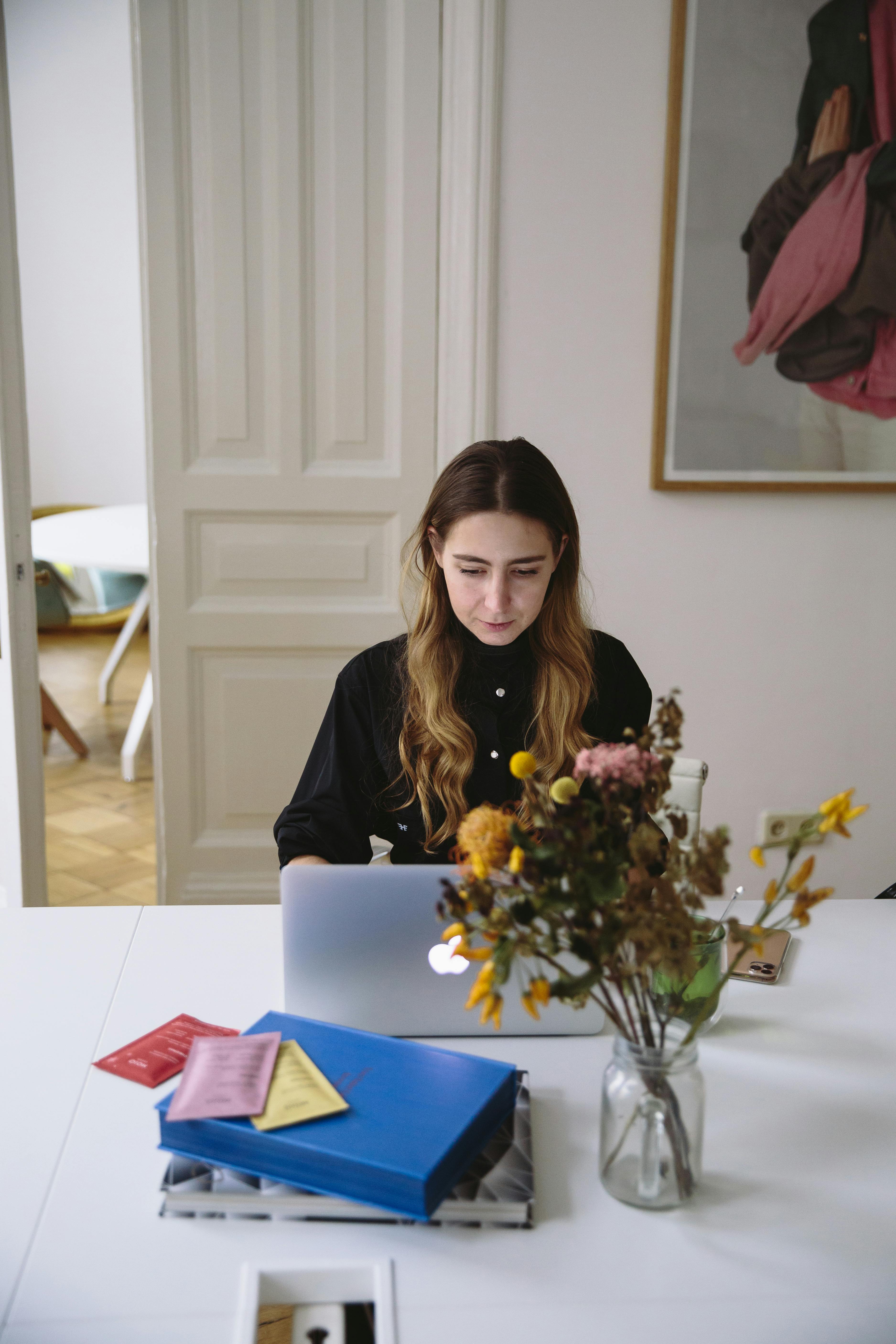 Young woman focused on laptop work in a well-organized home office.