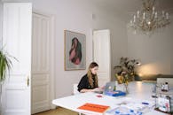 在现代家庭办公环境中，一位女性正使用笔记本电脑工作，周围摆放着装饰品和室内植物