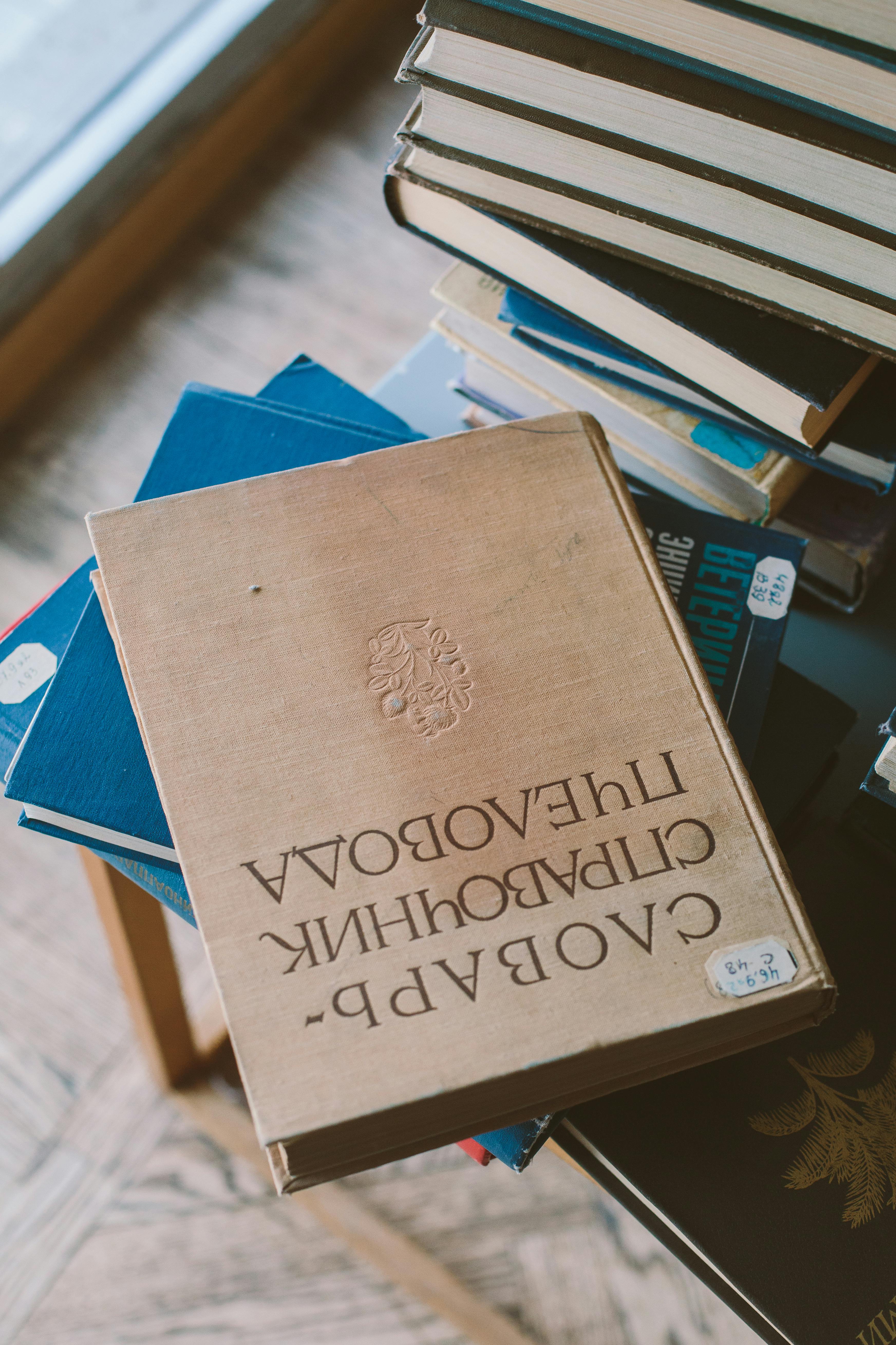 Two children sitting on the floor reading colorful illustrated books together.