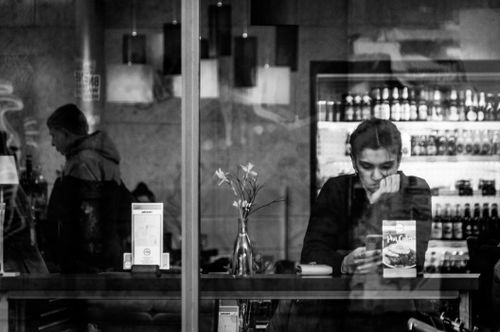 Free Black and white photo of people in a cafe seen through a glass window capturing a moment of reflection. Stock Photo