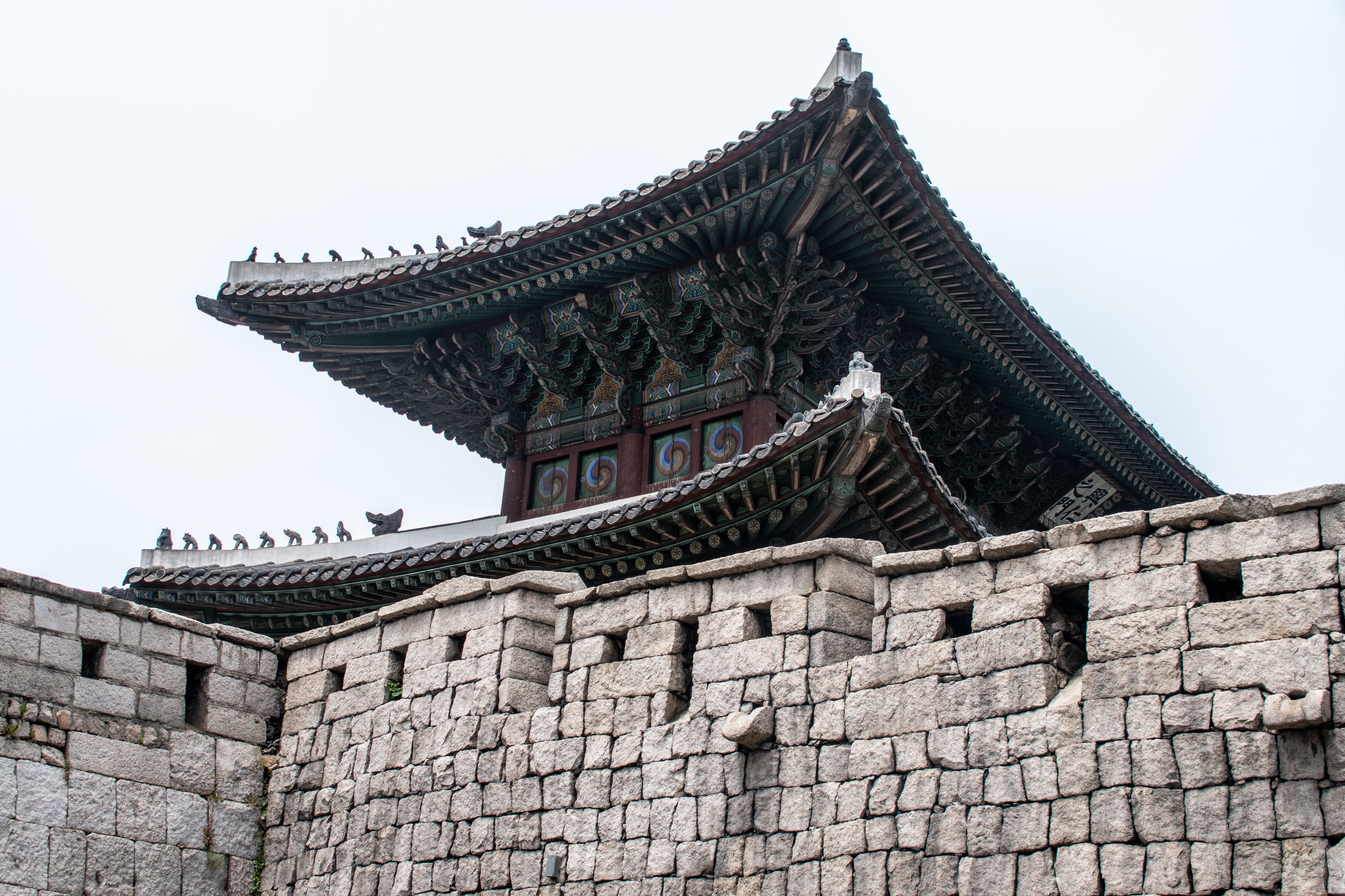 Close-up of traditional Korean fortress architecture showcasing detailed roof and stone walls.