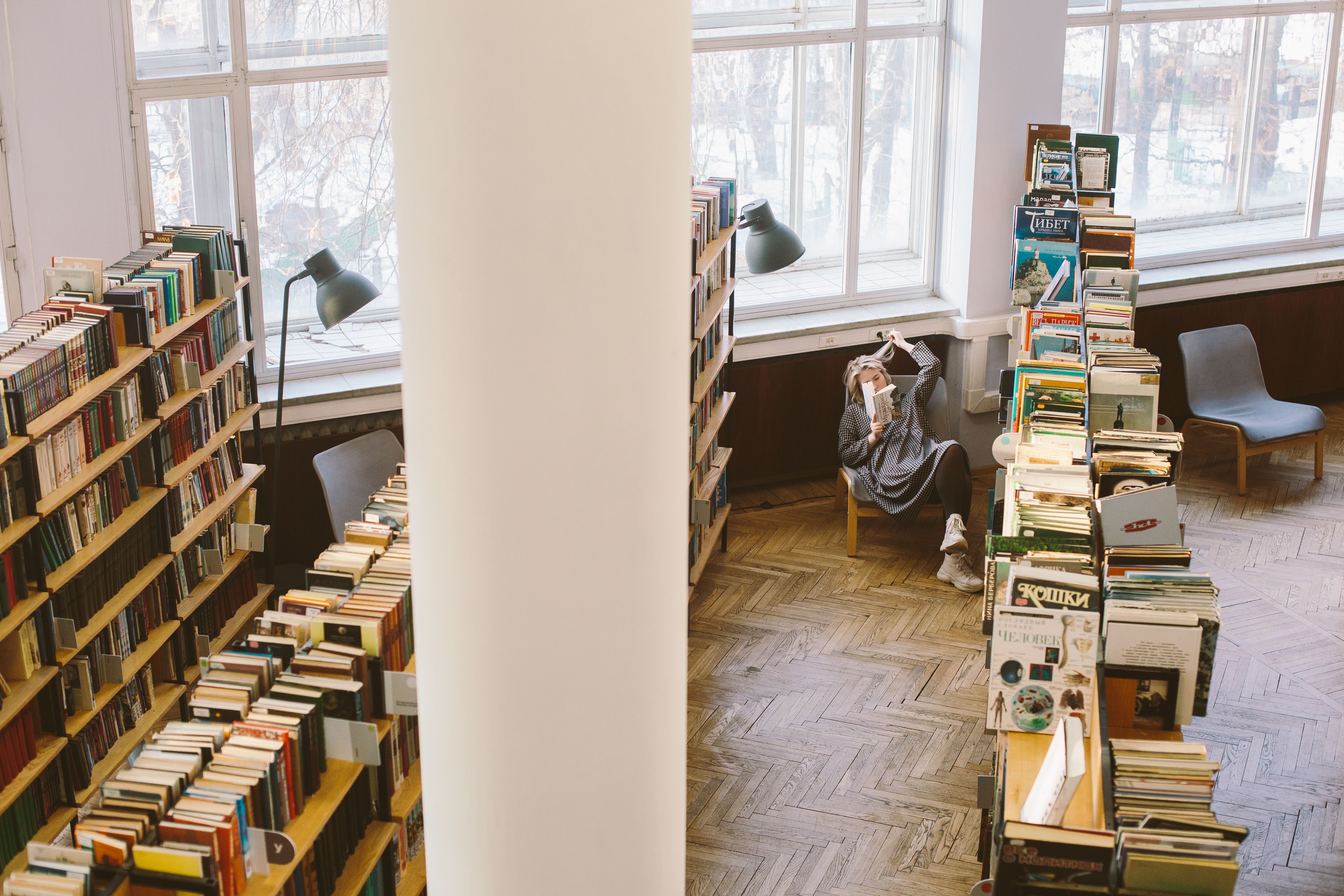 Man Standing Inside Library While Reading Book · Free Stock Photo