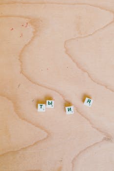 Image of Cyrillic Scrabble tiles spelling 'ты я' on a wooden surface.