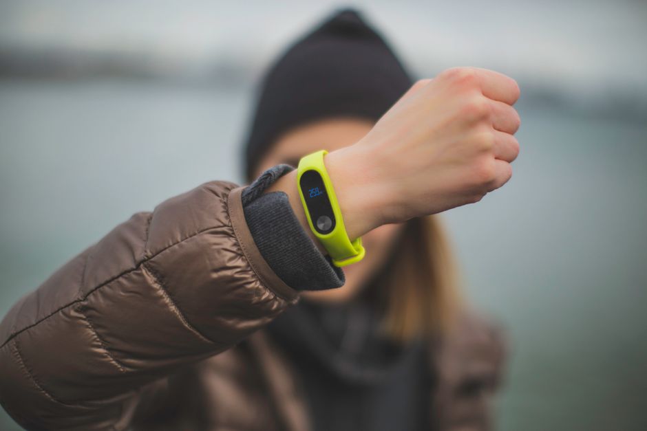 Close-up of a person holding up a fitness tracker, emphasizing technology and active lifestyle.