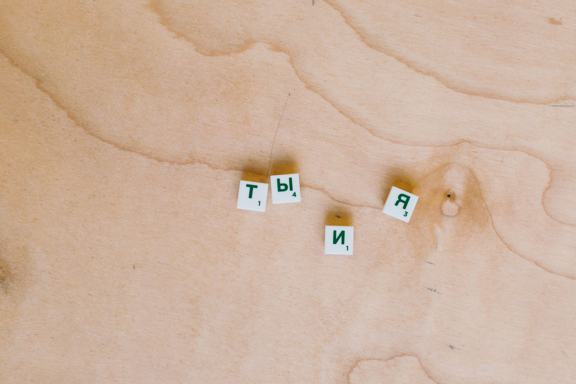 Cyrillic Scrabble tiles arranged on a wooden surface showcasing Russian text.