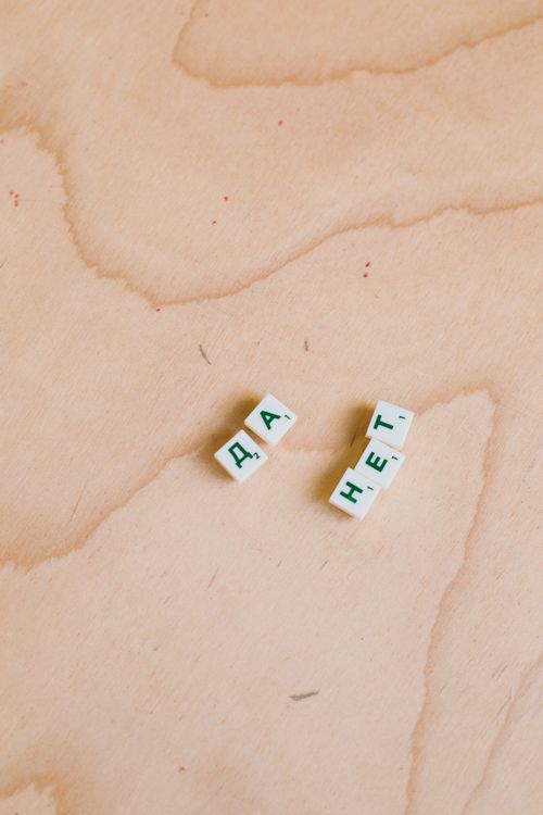 Free Cyrillic Scrabble tiles spelling words on a wooden background. Stock Photo