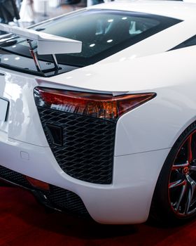 Elegant rear view of a white sports car on display, highlighting design and aerodynamics in a showroom setting.