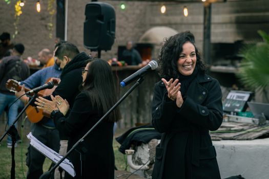 A joyful outdoor music event with live musicians and a smiling audience under string lights.