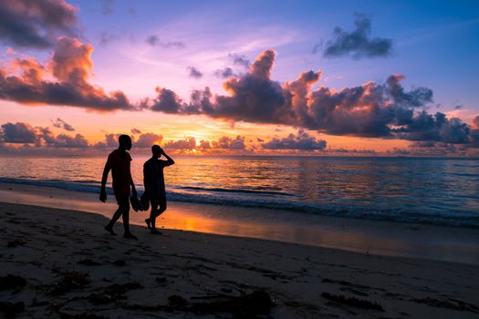 Silhouettes walking along Mombasa beach during a stunning sunrise.