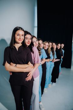 A group of diverse young women standing in a line indoors, showcasing unity and diversity.