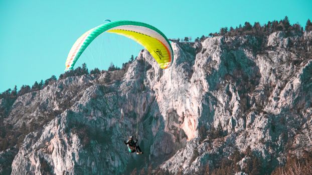 Experience the thrill of paragliding over stunning rocky landscapes under clear blue skies.