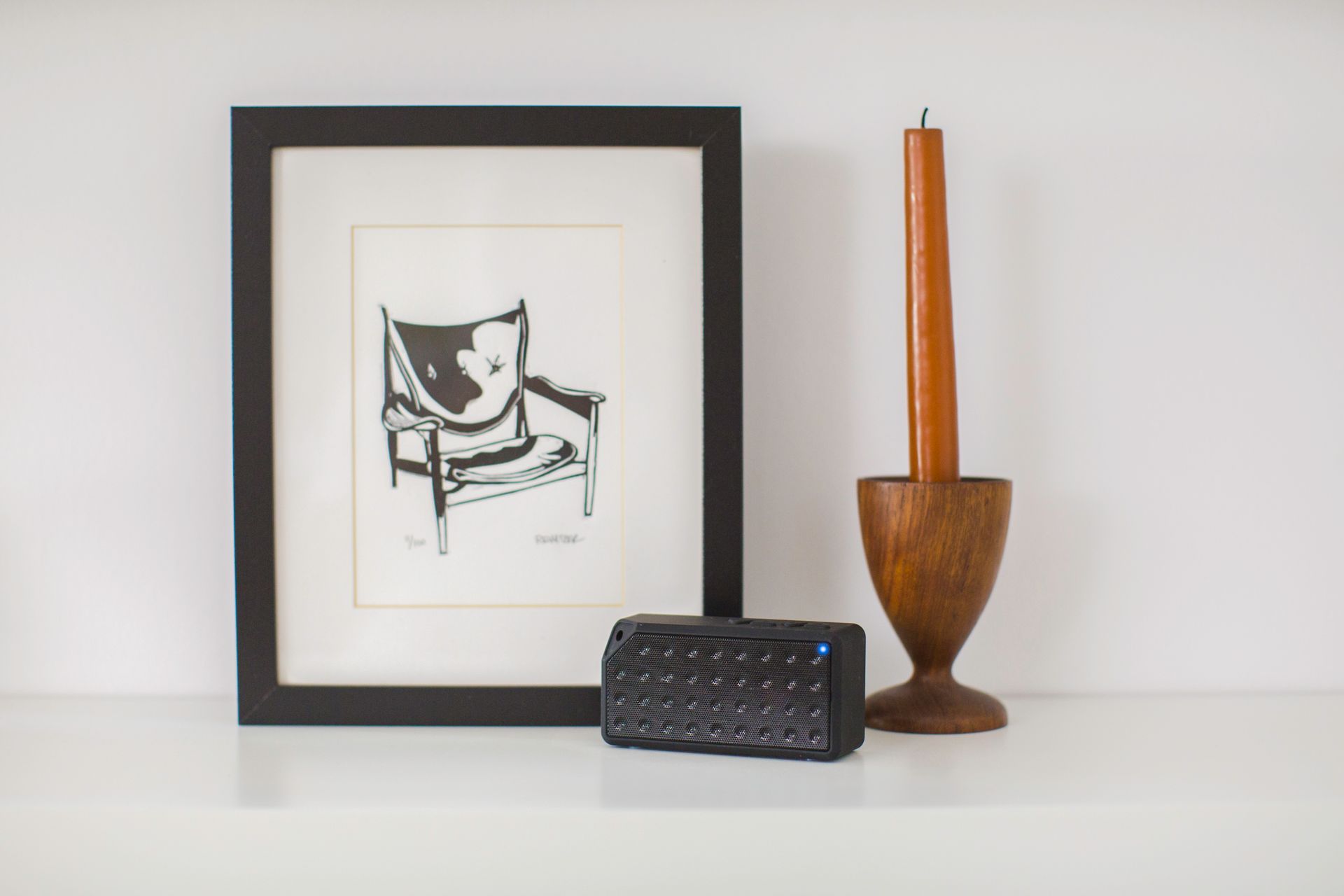 Contemporary minimalist decor with art, bluetooth speaker, and wooden candle holder.