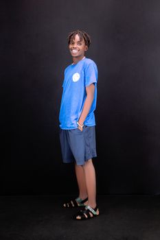 Smiling teenager in blue attire standing confidently against a black backdrop.