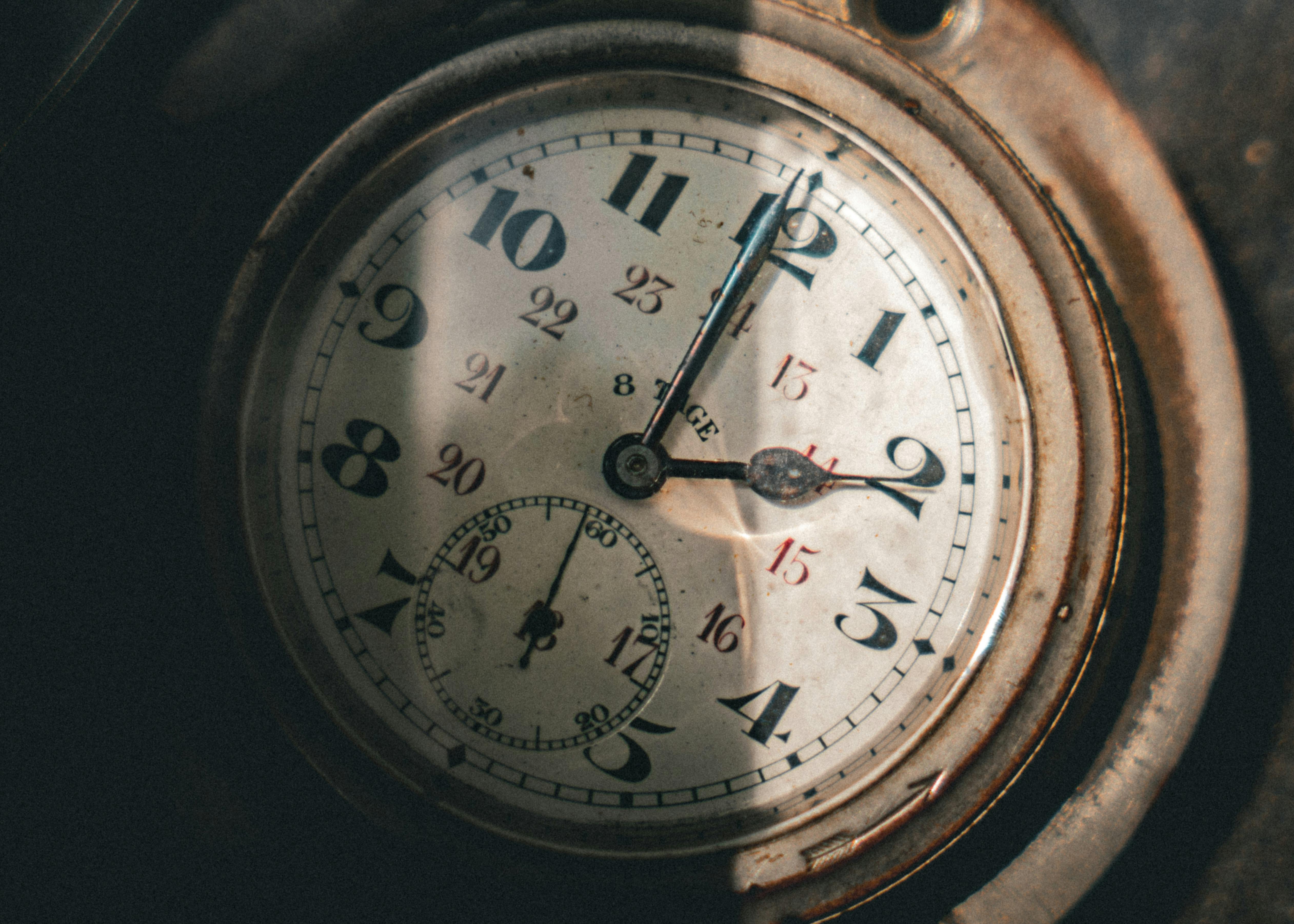 Close-up of a vintage pocket watch with intricate clock hands casting shadows.