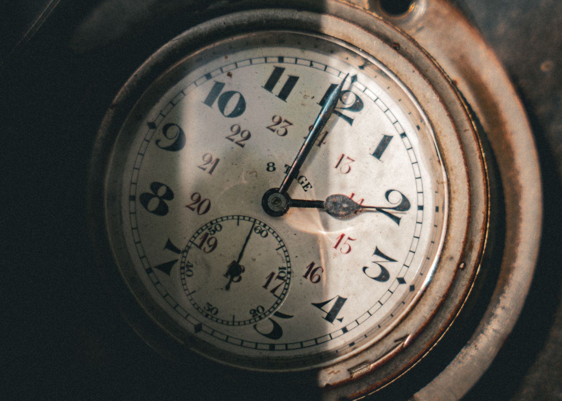 Close-up of a vintage pocket watch with intricate clock hands casting shadows.