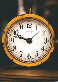 Close-up of a rustic yellow clock face showing ten o'clock, with vintage charm and 'Blessing' text.